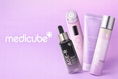 Stacked authentic Medicube skincare products including Age-R devices and Zero Pore pads on a lavender pink background with the official Medicube logo—authorized Seoul-direct collection for UAE and GCC markets at Korean-Skincare Arabia.